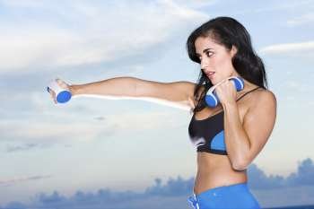 Side profile of a mid adult woman exercising with dumbbells