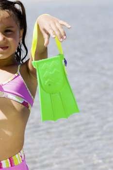 Girl holding a flipper on the beach