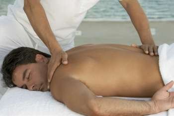 Close-up of a massage therapist massaging a mid adult man´s back