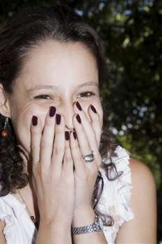 Portrait of a young woman covering her mouth with her hands