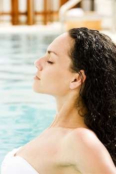 Side profile of a young woman with her eyes closed in a swimming pool
