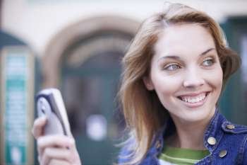 Close-up of a young woman smiling and holding a mobile phone 