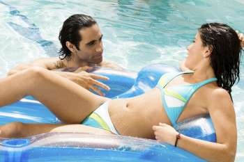 Close-up of a mid adult man and a young woman looking at each other in a swimming pool
