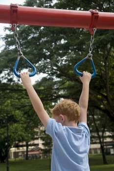 Rear view of a boy hanging on monkey bars
