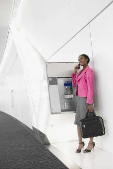 Side profile of a businesswoman talking on a pay phone at an airport