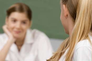 Two schoolgirls looking at each other in a classroom