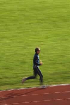 Side profile of a mid adult man running on a running track