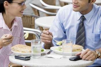 Businessman and a businesswoman having lunch at a sidewalk cafe