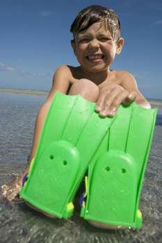 Portrait of a boy wearing flippers and sitting on the beach