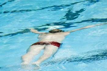 Rear view of a mid adult man swimming in a swimming pool