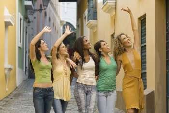 Five teenage girls standing together and waving