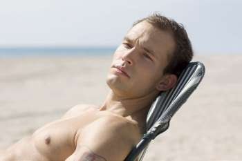 Side profile of a young man relaxing on the beach