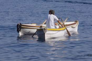 Rear view of two men sitting in boats, Capri, Campania, Italy