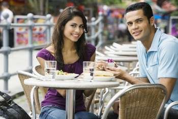 Portrait of a mid adult man proposing to a young woman at a sidewalk cafe