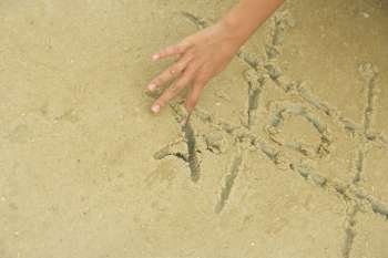 Close-up of a person´s hand playing tic-tac-toe in sand