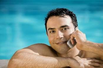 Portrait of a young man talking on a mobile phone in a swimming pool