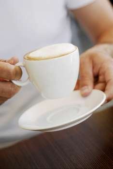 Mid section view of a person holding a coffee cup