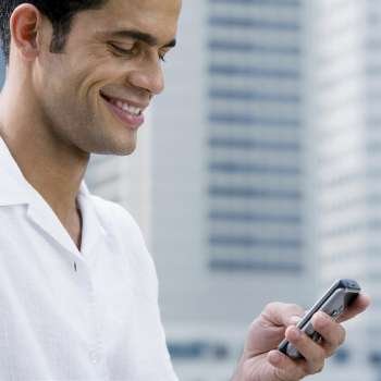 Close-up of a mid adult man text messaging and smiling