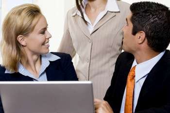 Close-up of a businessman and two businesswomen talking in front of a laptop