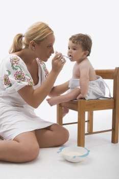 Mid adult woman feeding her son with a spoon