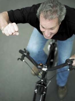 High angle view of a mature man cycling with his hand raised