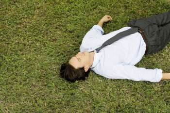 High angle view of a businessman lying on the grass