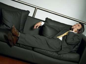 Businessman reclining on a couch and talking on a mobile phone