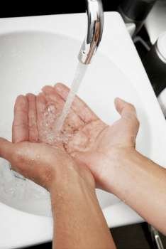 Close-up of a man washing his hands in the bathroom sink