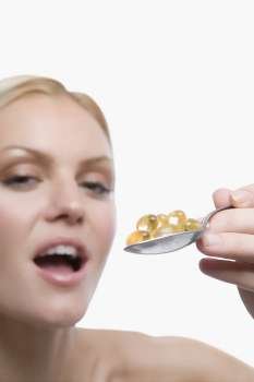 Portrait of a young woman holding a spoon full of pills