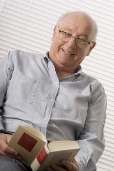 Close-up of a senior man reading a book and smiling