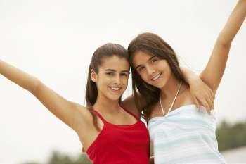 Portrait of two girl smiling with their hands raised