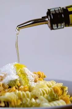 Olive oil being poured on a plate of pasta