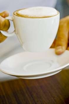 Mid section view of a person holding a coffee cup