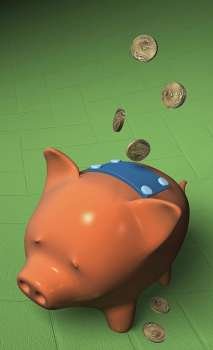 High angle view of coins falling on a piggy bank