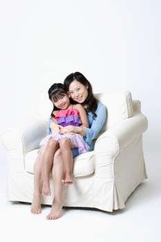 Portrait of a young woman sitting in an armchair with her daughter on her lap
