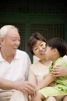 Side profile of a boy sitting with his grandparents and smiling