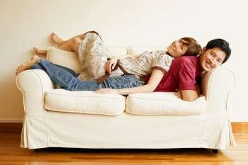 Portrait of a young couple lying back to back on a couch
