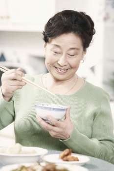 Close-up of a senior woman holding chopsticks and a bowl