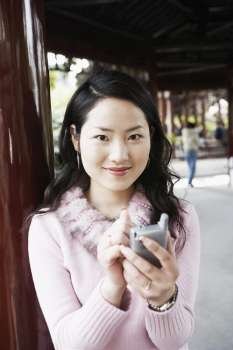 Portrait of a young woman operating a mobile phone with a digitized pen