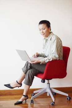 Portrait of a businesswoman sitting in an armchair and using a laptop