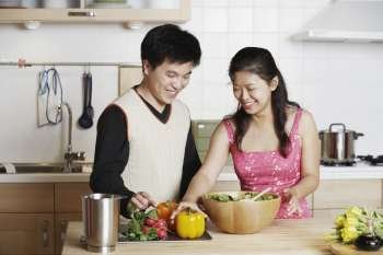 Close-up of a young man standing with a mid adult woman in the kitchen