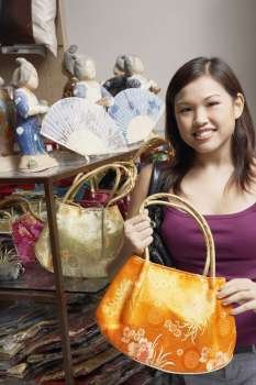 Portrait of a young woman choosing a hand bag and smiling