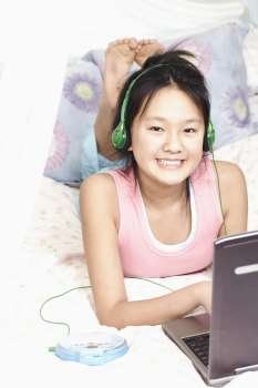 Portrait of a girl using a laptop and listening to music on an MP3 player