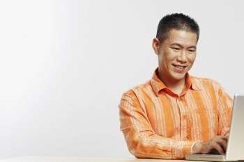 Mid adult man using a laptop and smiling