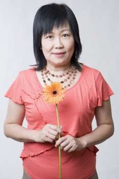 Portrait of a mature woman holding a daisy flower