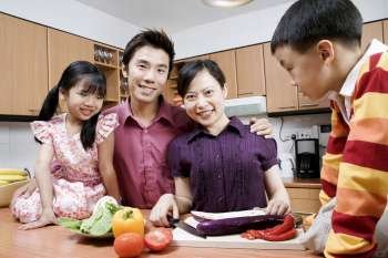 Portrait of a mid adult man and a young woman with their children in a domestic kitchen