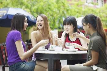 Four young women sitting in an outdoor restaurant