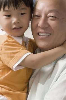 Close-up of a mature man smiling and carrying his grandson