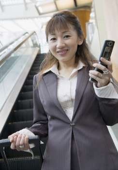 Portrait of a businesswoman holding a mobile phone and a suitcase
