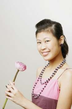 Portrait of a young woman holding a lotus flower and smiling